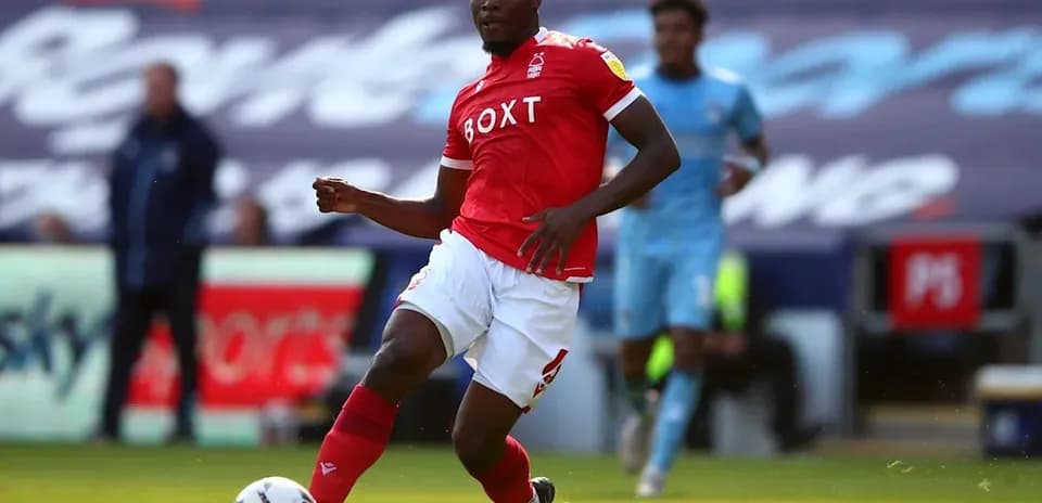 Futbolchi qizil forma kiyib, to'pni ushlamoqda