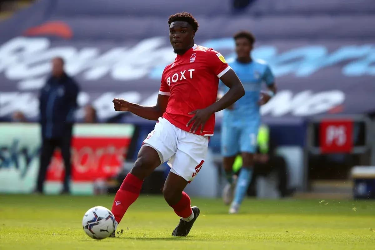 Futbolchi qizil forma kiyib, to'pni ushlamoqda