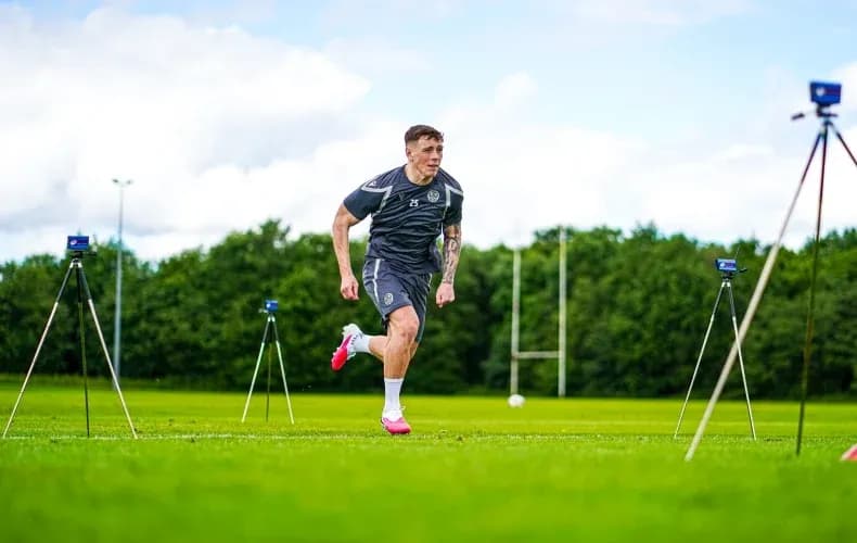 Futbolchi mashg'ulotda yugurmoqda, o'lchov asboblari bor