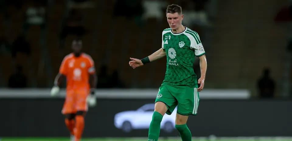 Futbolchi to'pni nazorat qilmoqda, darvozabon orqa planda