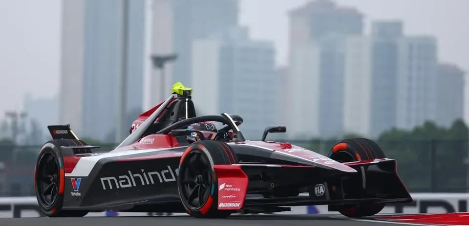 Mahindra racing car on track with city skyline background