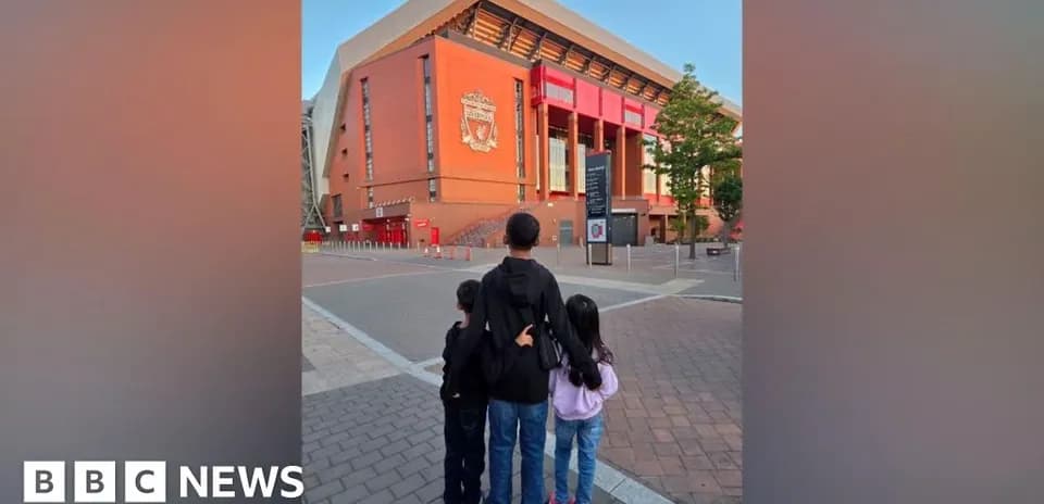 Three children standing in front of Anfield stadium