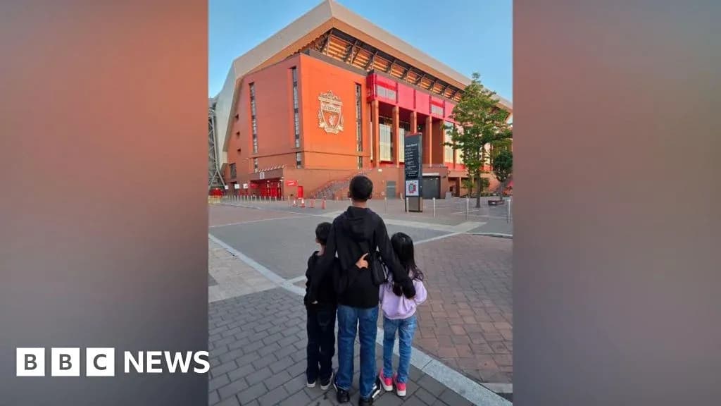Three children standing in front of Anfield stadium