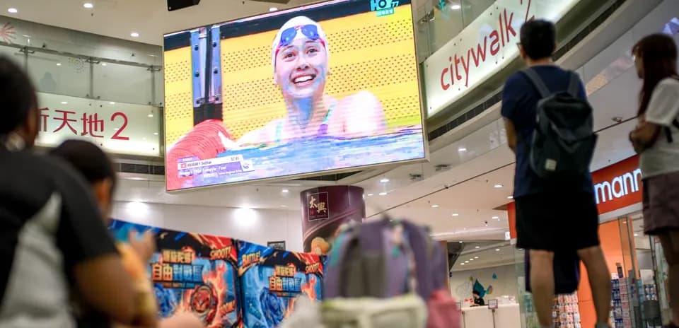 People watching swimming competition on large screen