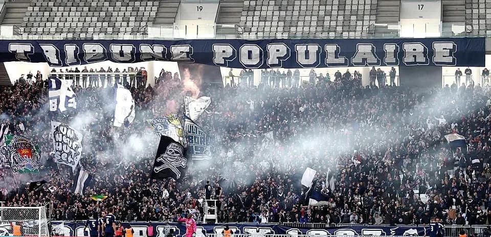 Stadium crowd with banners and smoke during match