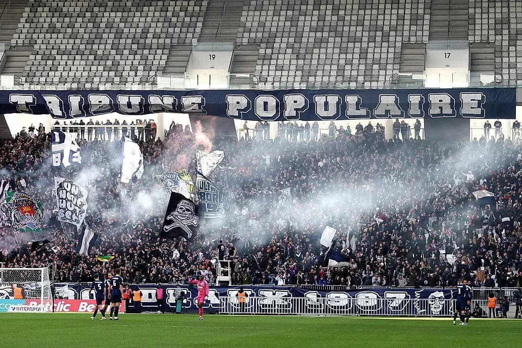 Stadium crowd with banners and smoke during match