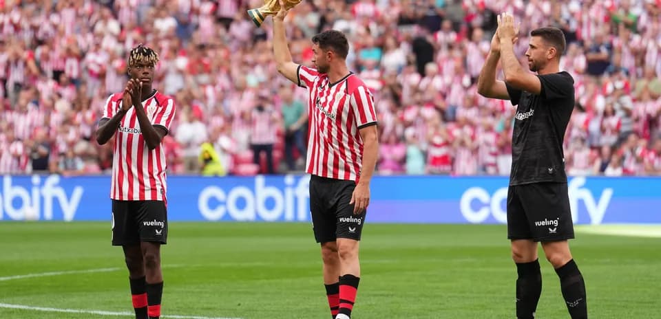 Athletic Bilbao players celebrating with trophy on pitch