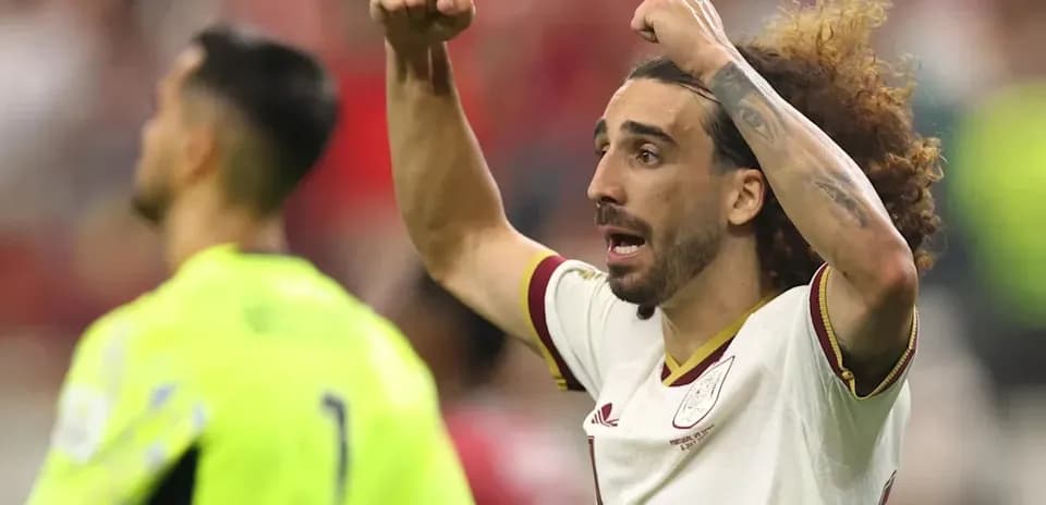 Futbolchi maydonda qo'llarini ko'tarib xursandchilik qilmoqda