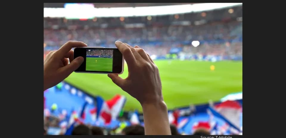 Fan recording football match with smartphone in stadium
