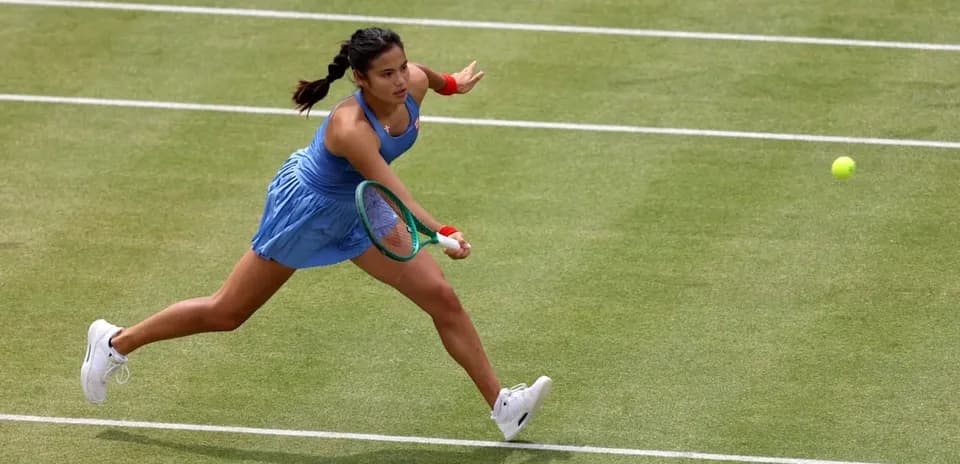Tennis player reaching for a ball on court