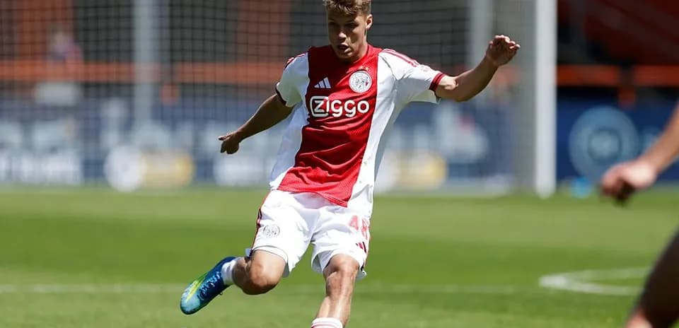 Futbolchi Ajax formasi bilan to'p urmoqda