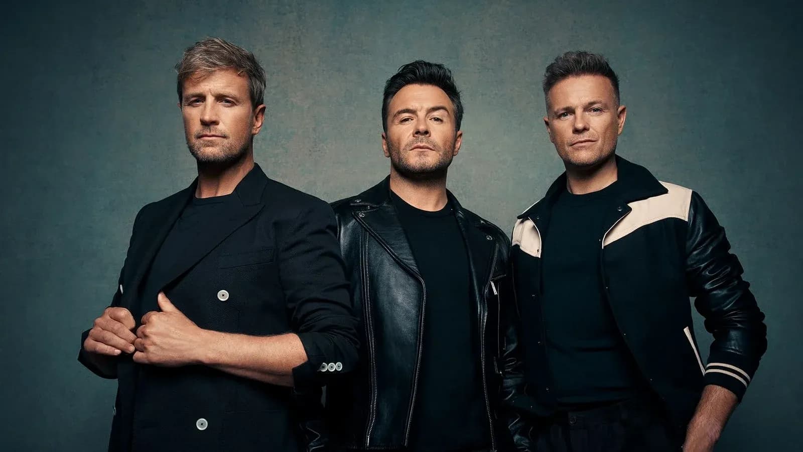 Three men posing together against a textured backdrop