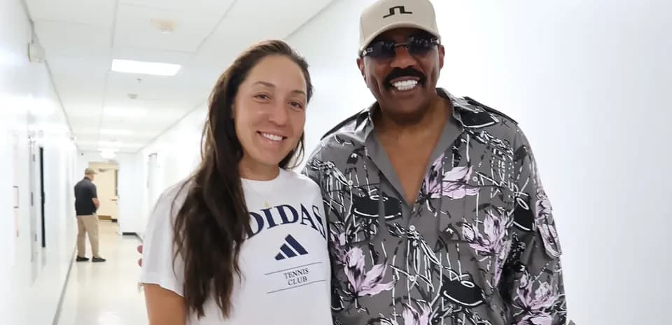 Tennis player posing with a man in hallway