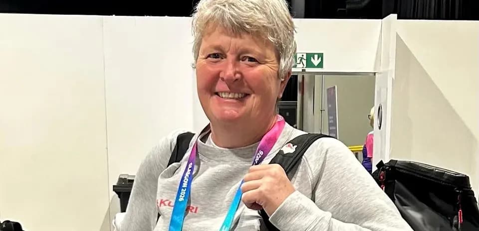 Woman smiling with sports accreditation lanyard around neck