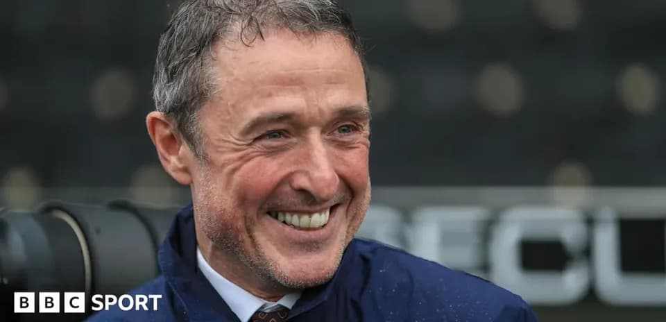 Coach smiling during a rainy match day