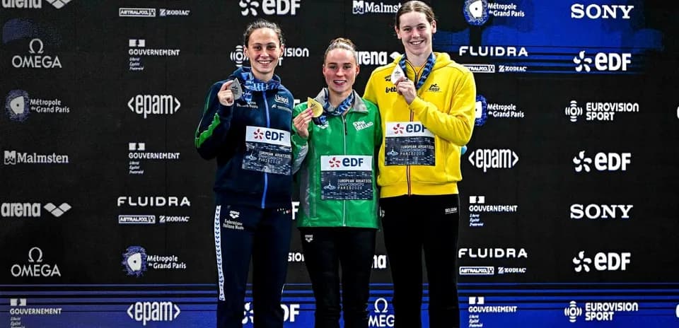 Three swimmers celebrating on podium with medals