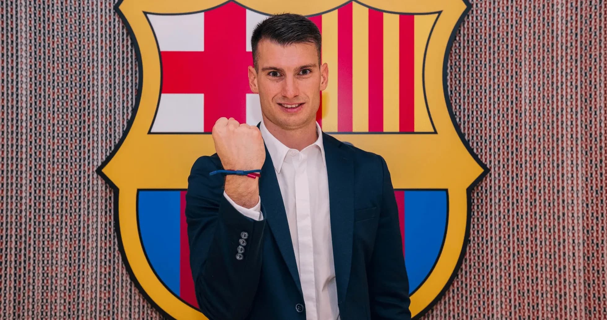 Yoshinori Muto standing in front of Barcelona logo