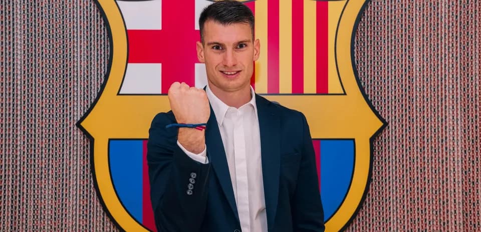 Yoshinori Muto standing in front of Barcelona logo