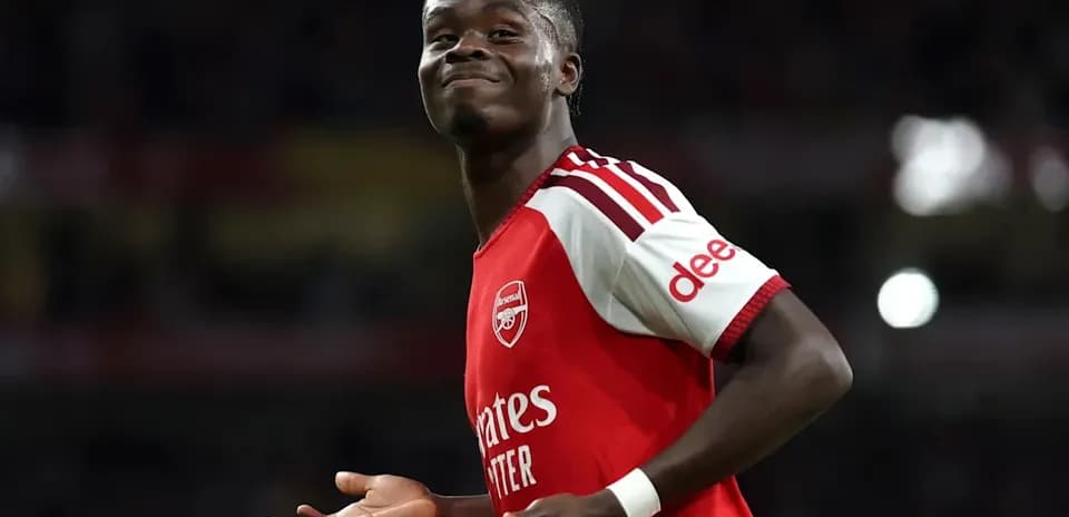 Futbolchi Arsenal futbolka kiygan, xursand ko'rinmoqda