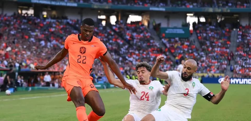 Holland player dribbling past two Moroccan defenders