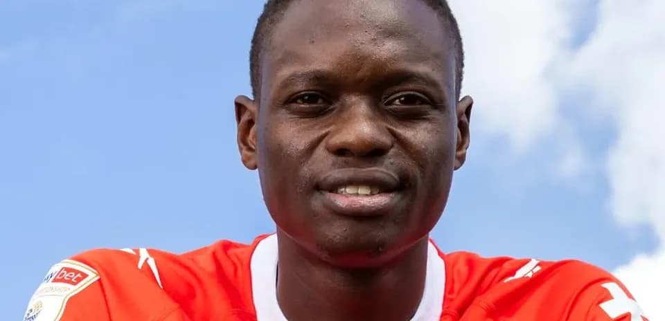 Futbolchi qizil forma kiygan, ko'k osmon fonida