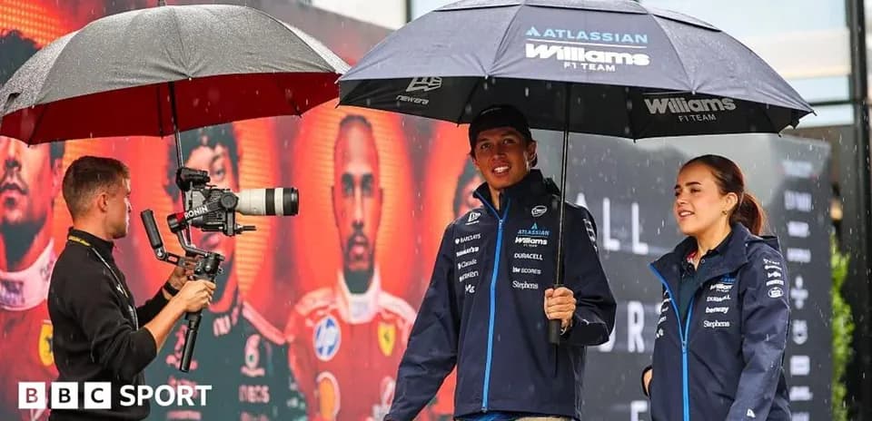 Williams F1 team members under umbrellas during rain