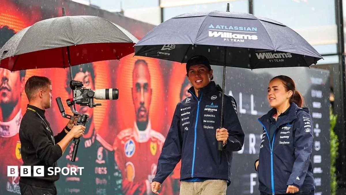 Williams F1 team members under umbrellas during rain