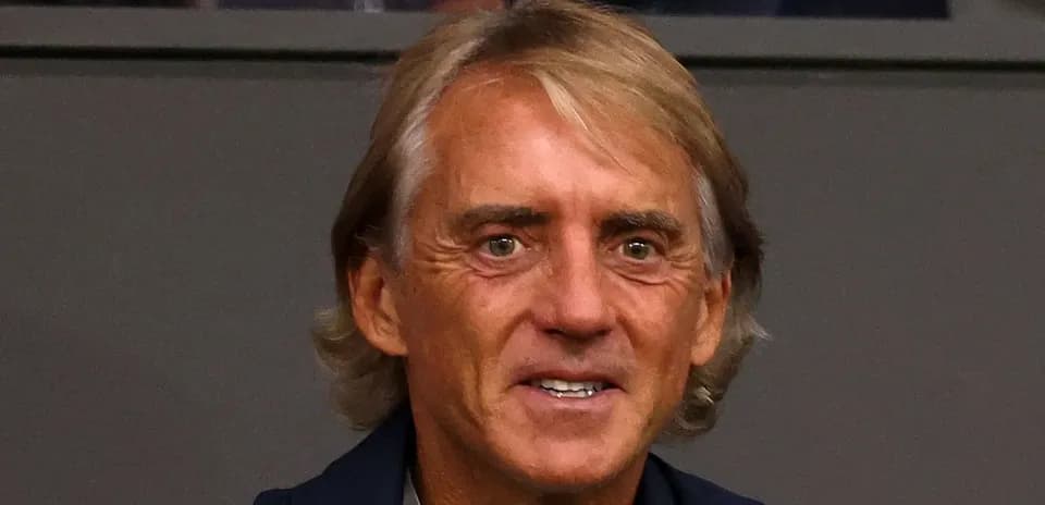 Shaggy-haired man smiling in a stadium setting