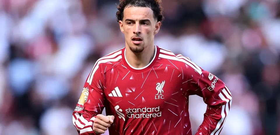 Futbolchi Liverpool formasida maydonda yugurmoqda