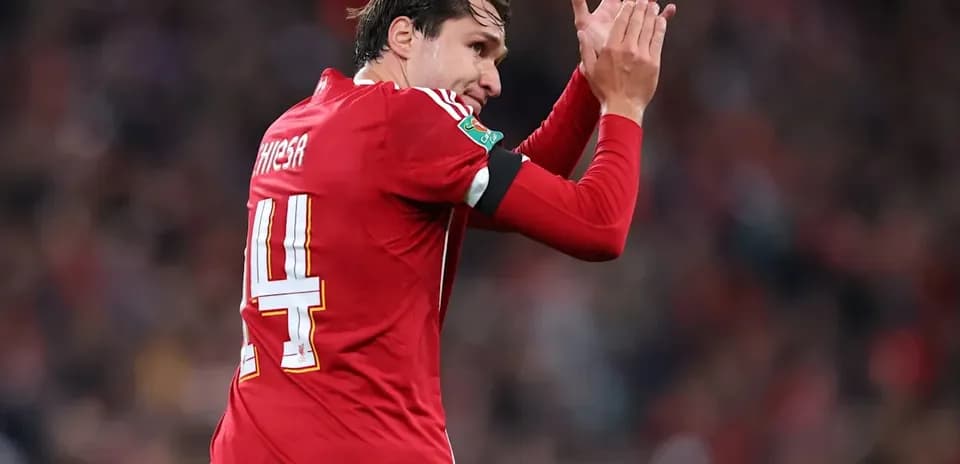 Futbolchi maydonda qo'llarini ko'tarib olqishlayapti