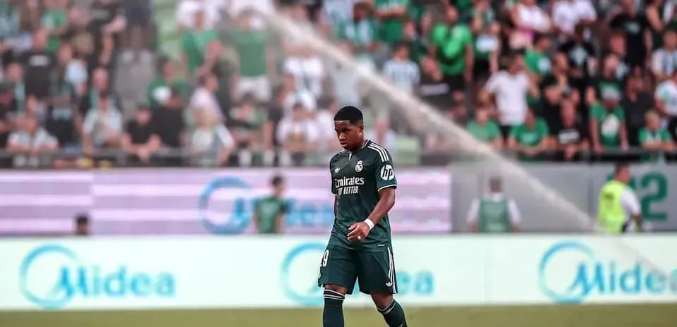 Futbolchi maydonda yurib, tomoshabinlar orqasida