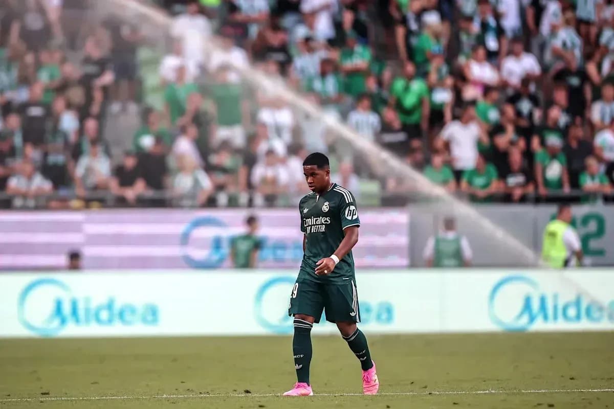 Futbolchi maydonda yurib, tomoshabinlar orqasida