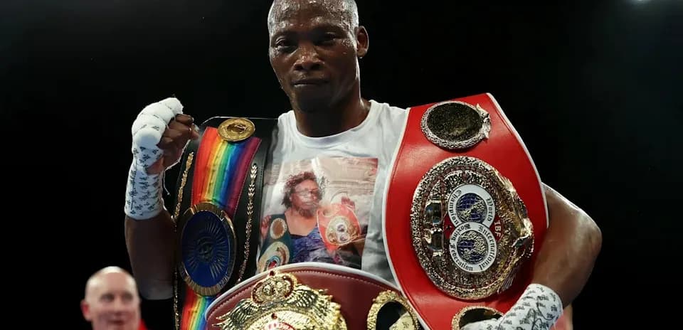 Boxer holding multiple championship belts after victory