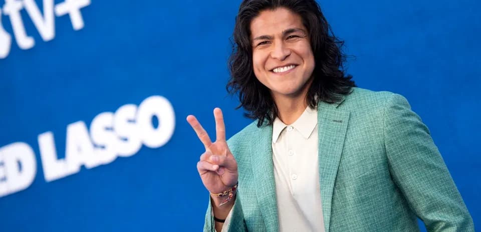 Person smiling and making peace sign at event