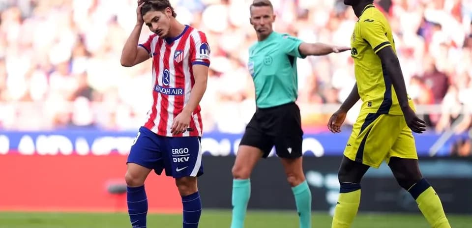 Atlético Madrid player reacts during match with referee