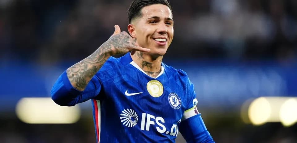Futbolchi Chelsea formasida qo'l telefoni belgisini ko'rsatmoqda