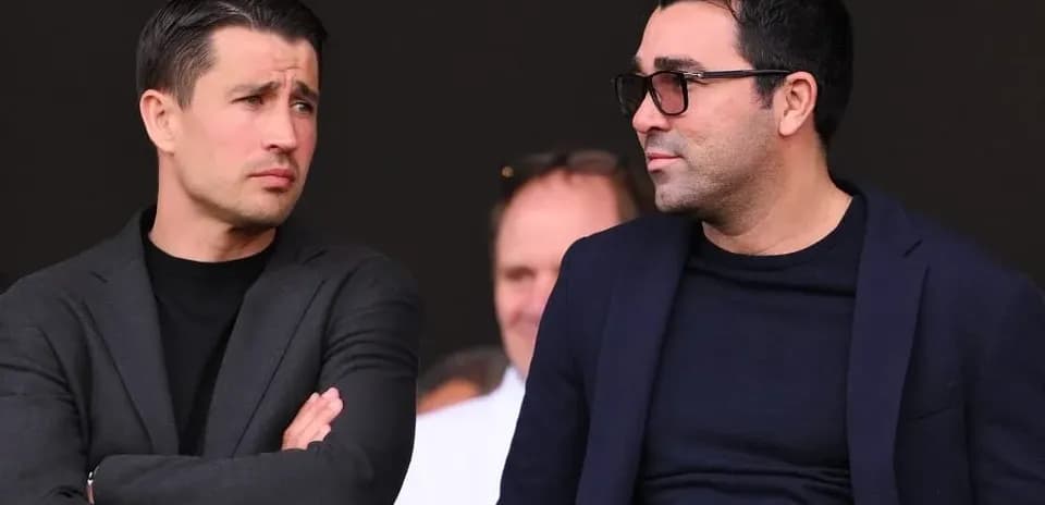 Two men conversing in a sports venue