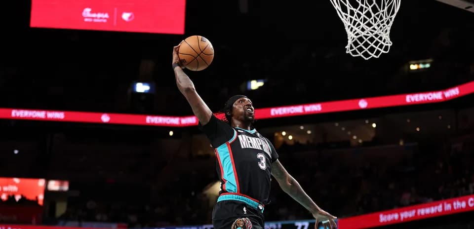 O'yinchi slam dunk qilmoqda, stadionda banner ko'rinmoqda