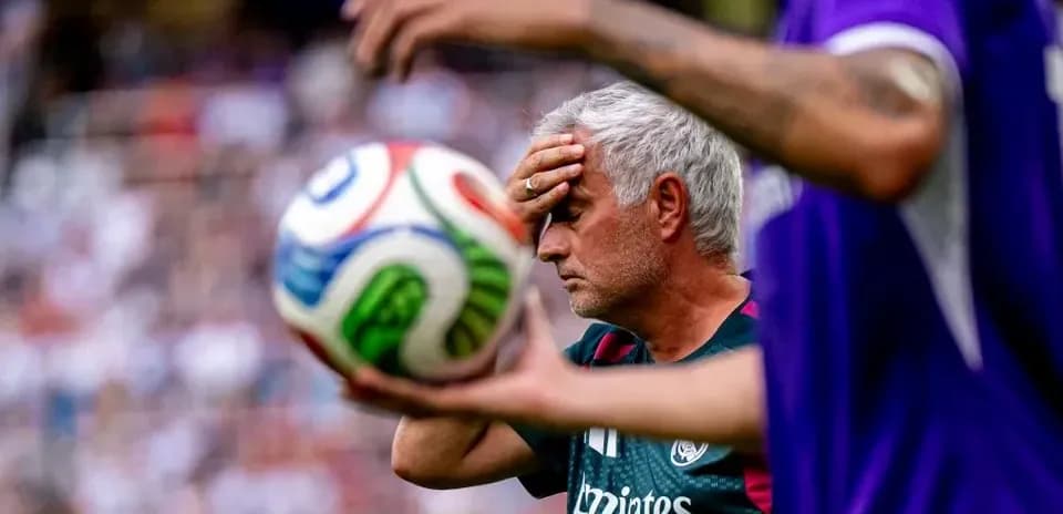 Trener o'ynayotgan futbol o'yinida to'p ushlab turibdi