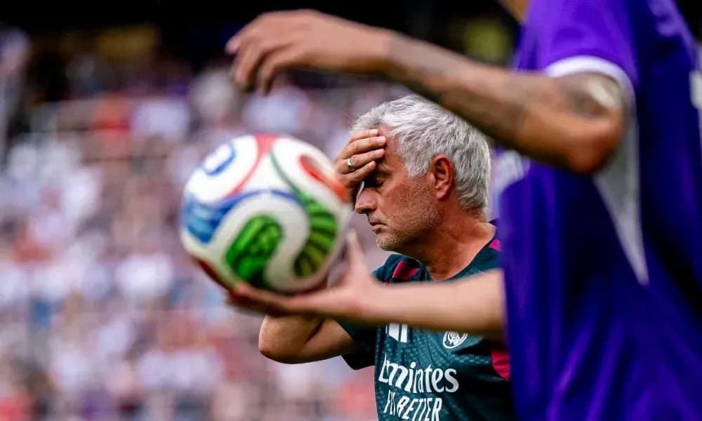 Trener o'ynayotgan futbol o'yinida to'p ushlab turibdi