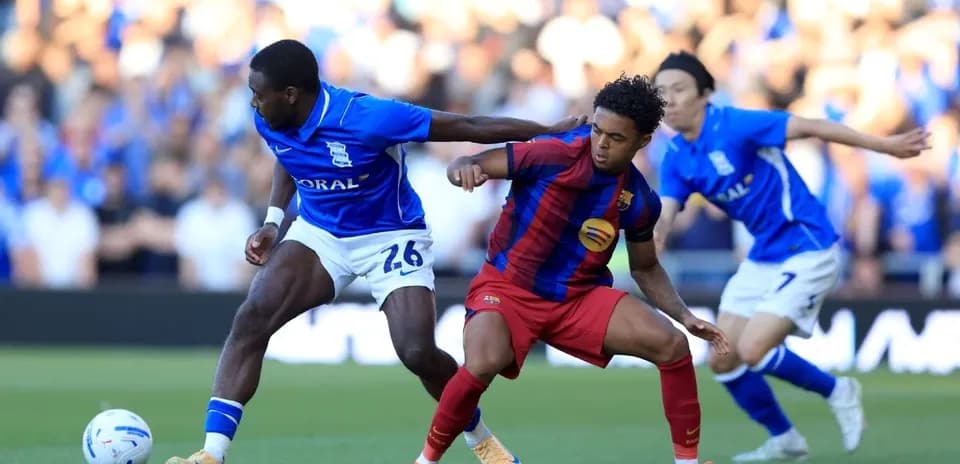 Birmingham player tackling Barcelona player during match