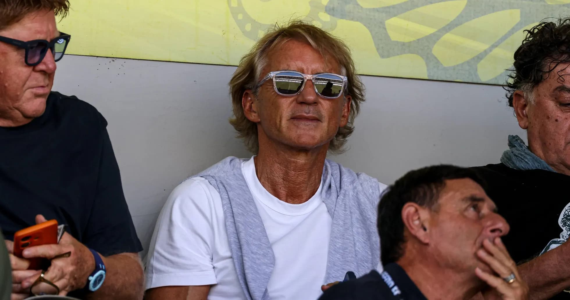 Man in sunglasses sitting with friends in stands