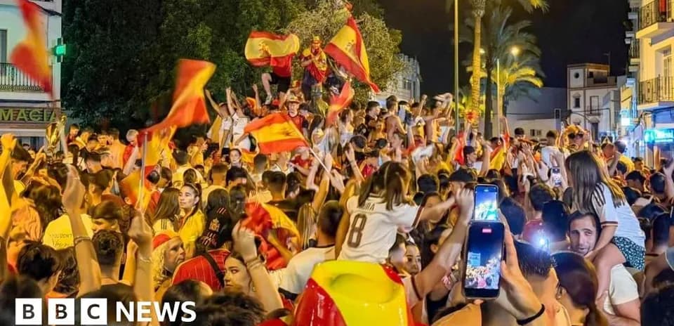 Jubilation of fans waving Spanish flags at night