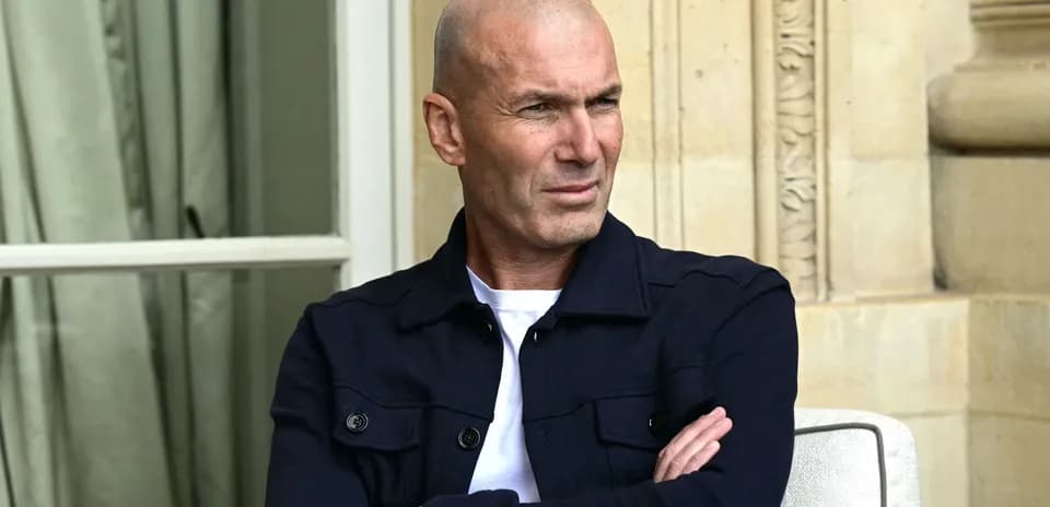 Bald man sitting with arms crossed outdoors