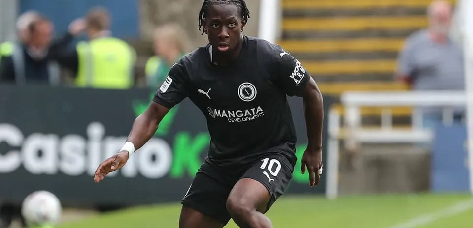 Futbolchi qora forma kiygan, harakatda