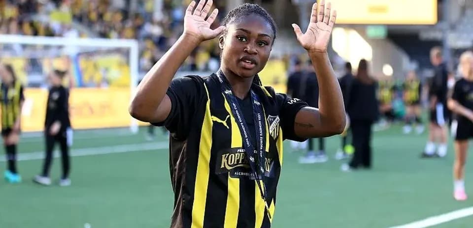 Futbolchi maydonda qo'lini ko'tarib turibdi