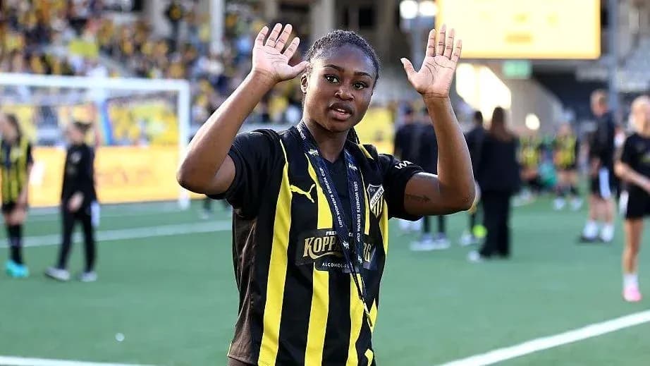 Futbolchi maydonda qo'lini ko'tarib turibdi