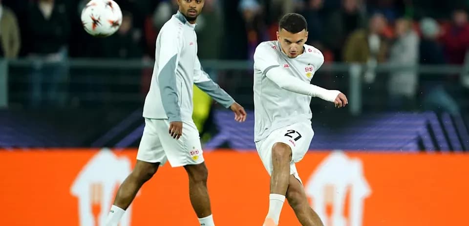 Futbolchi to'pni zarba berayotgani, boshqa futbolchi yaqinida