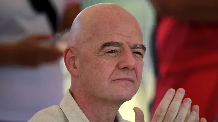 Man with bald head seated, hands clasped together