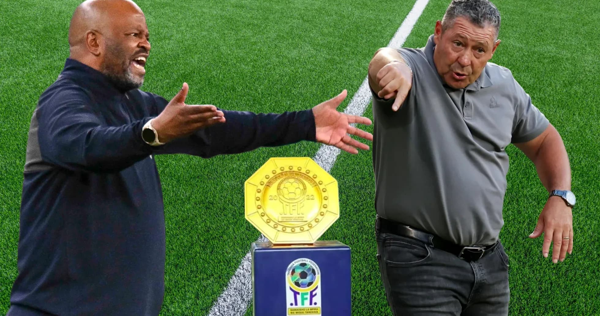 Two coaches gesturing beside a trophy on field